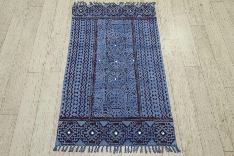 A blue, patterned rug lies on wood flooring.