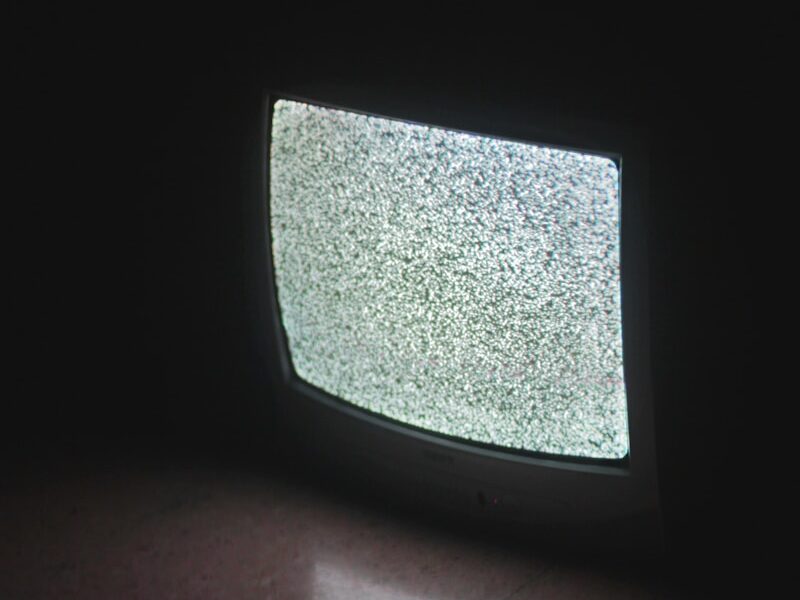 gray crt tv turned on in a dark room