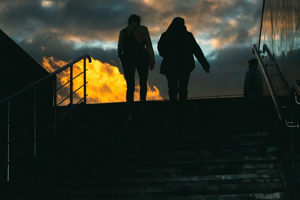 Two people walk up stairs at dusk.
