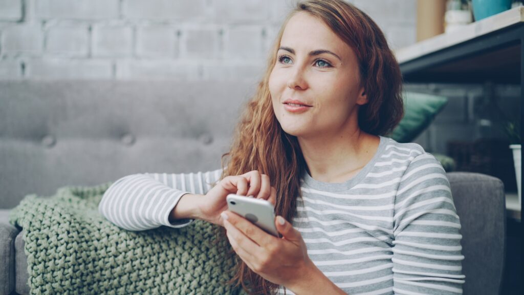 Woman holding a smartphone while sitting on a couch