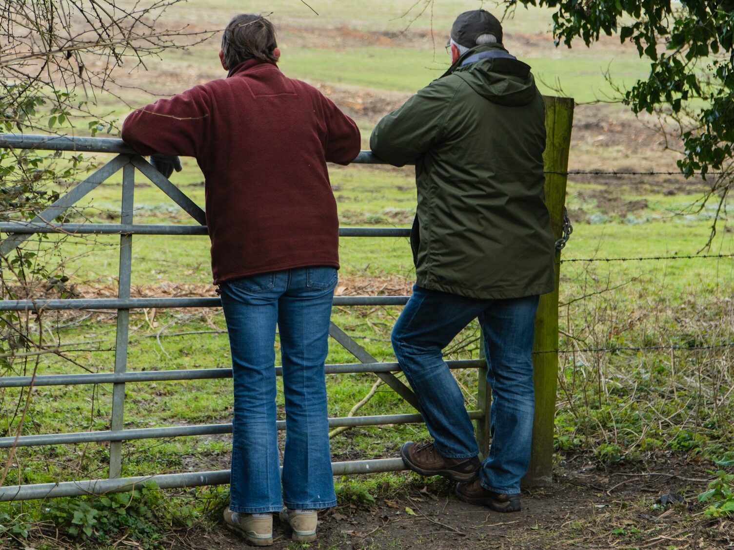 man and woman standing beside fence during daytime