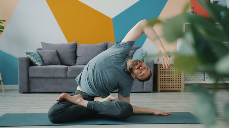 Man in yoga pose on mat in living room