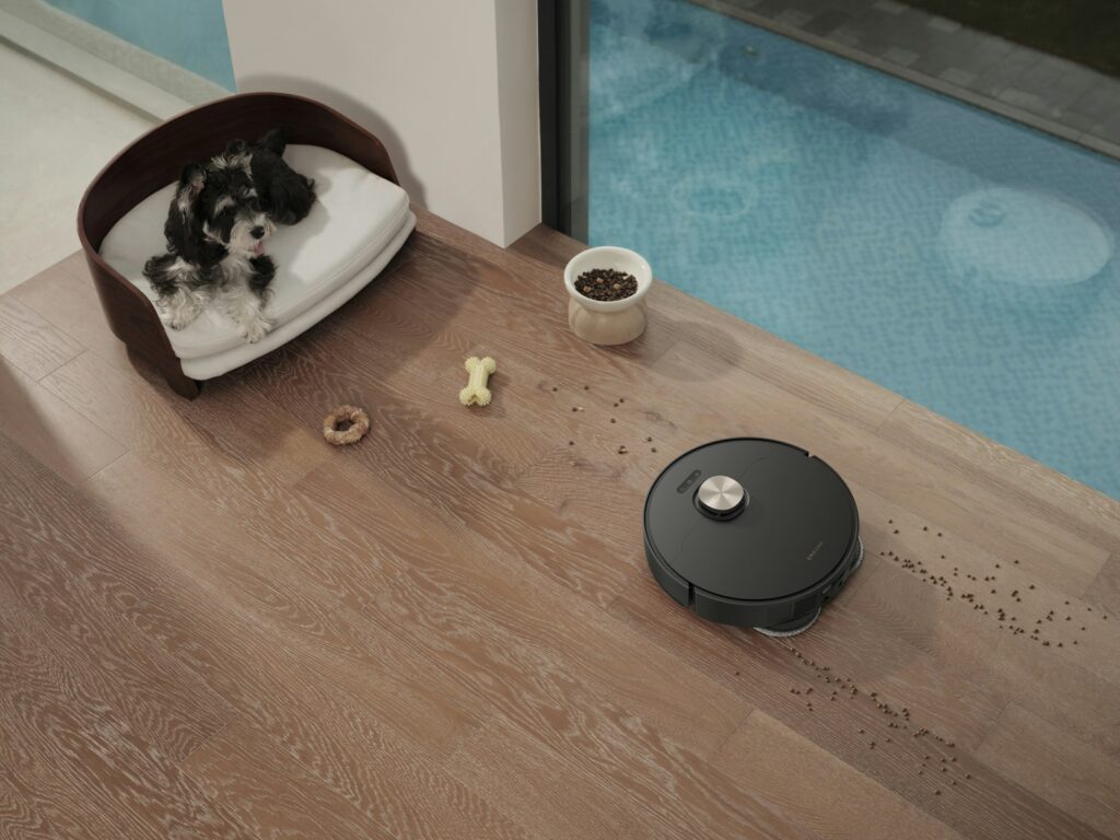 Robot vacuum cleaning a wooden floor near a dog bed