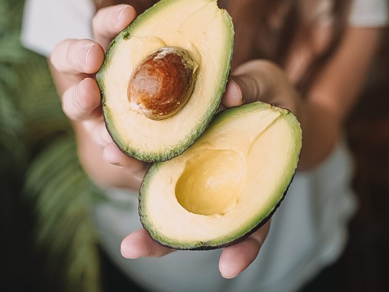sliced avocado fruit on persons hand