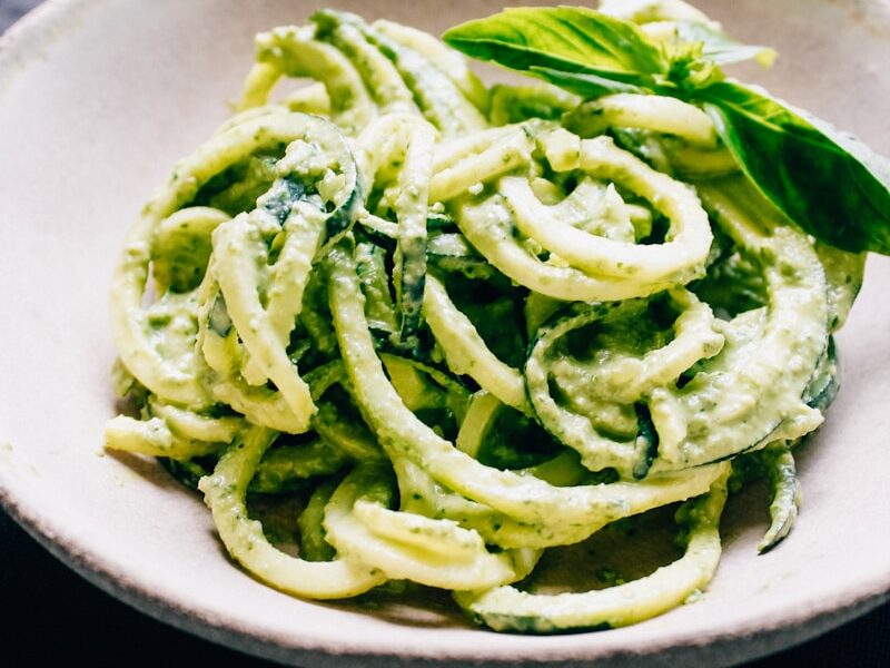 a white bowl filled with pesto pasta on top of a table