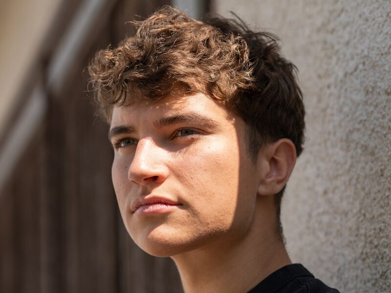 A young man standing next to a building