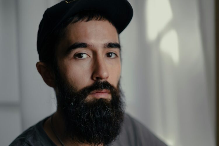 a man with a beard wearing a black hat