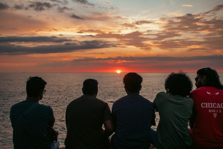 Friends watch the sunset over the ocean.