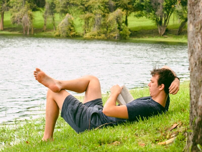 man on grass while reading book