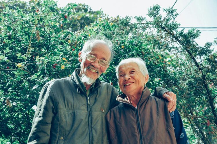 Senior couple enjoying a joyful moment together in a lush garden setting, exuding love and happiness.