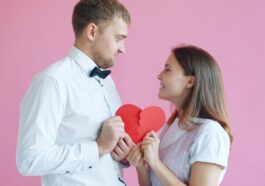 Couple holding a broken heart on pink background