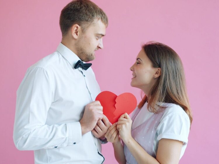 Couple holding a broken heart on pink background