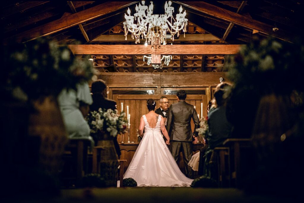 Charming indoor wedding ceremony with bride and groom at the altar, under a chandelier.
