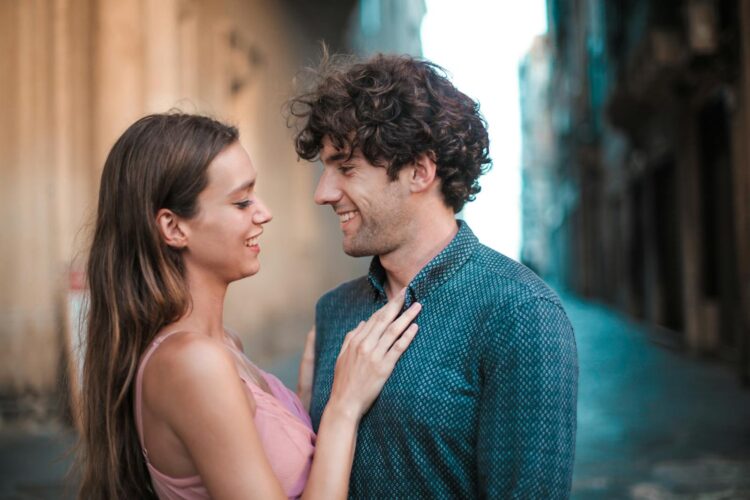 A happy young couple embracing and smiling while enjoying a romantic moment outdoors.