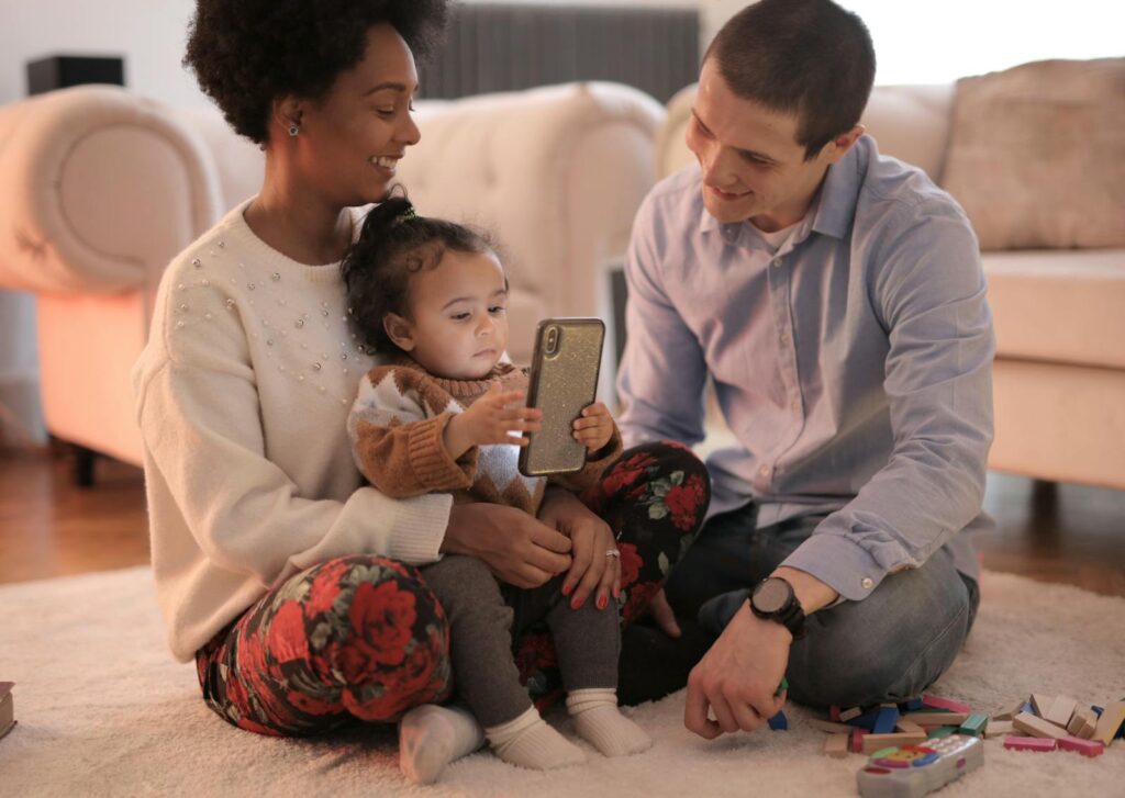 A happy family enjoys bonding time using a smartphone in a cozy living room.