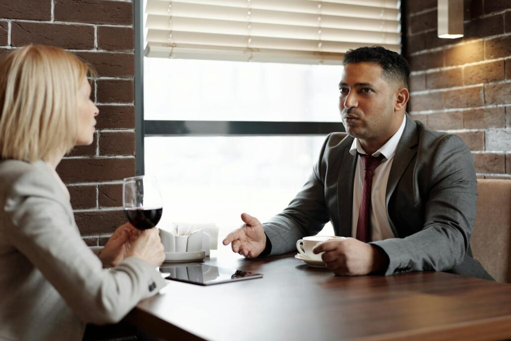 Two business professionals discussing over coffee and wine in a contemporary café.
