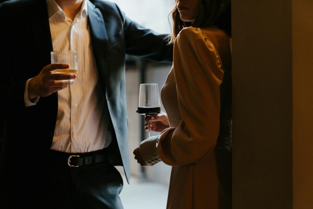 A stylishly dressed couple sharing a romantic moment with drinks at an upscale venue.