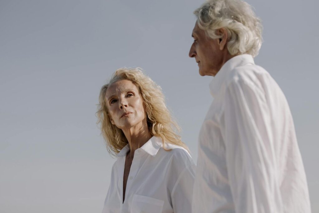 Elderly couple in white shirts gazing thoughtfully, capturing warmth and wisdom.
