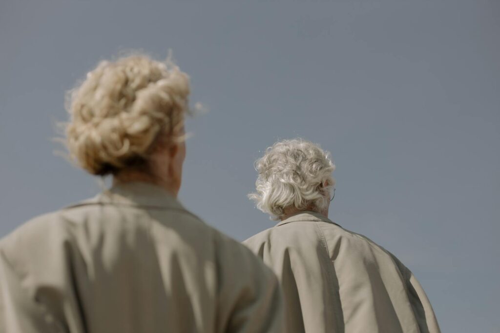 Back view of a couple in trench coats gazing at a clear sky, symbolizing togetherness.