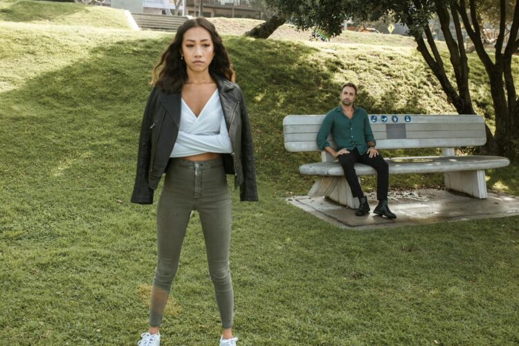 An upset couple having a disagreement while sitting on a bench in a park.