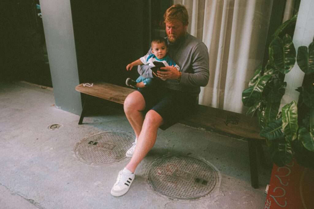a man sitting on a bench holding a baby