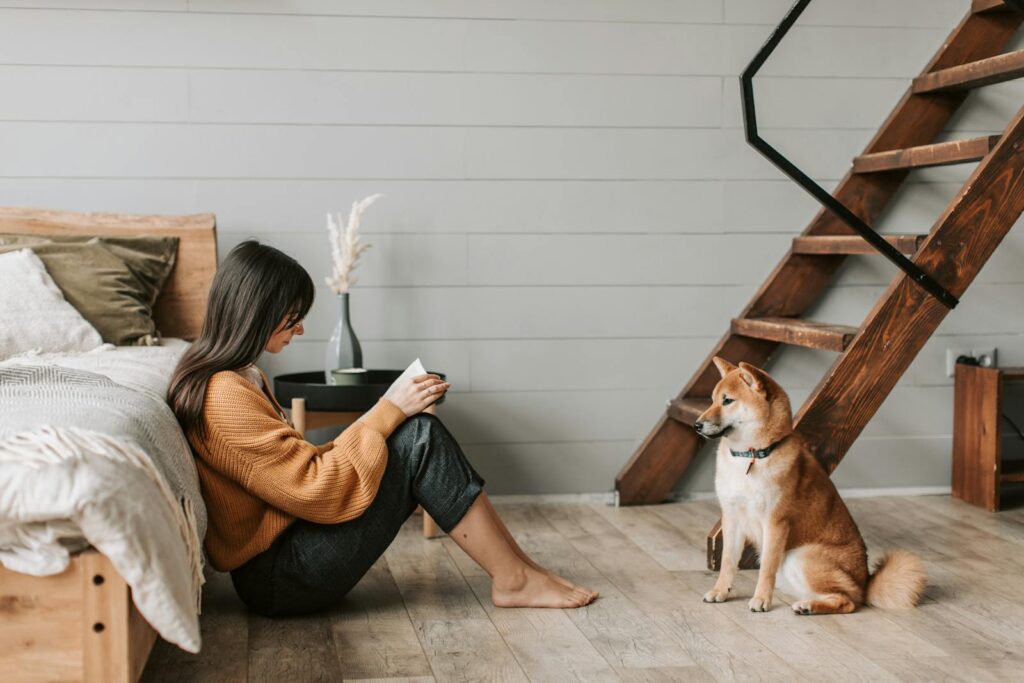 Woman reading a book with her Shiba Inu dog at home, a cozy and relaxing scene.