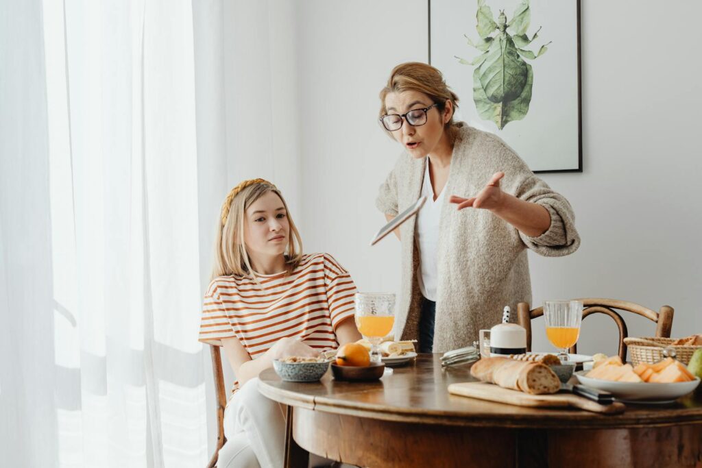 A mother and teenage daughter having a tense breakfast conversation at home.