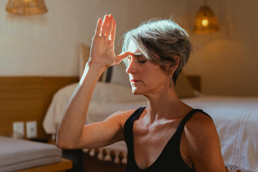 Serene elderly woman practicing yoga meditation indoors, symbolizing wellness and positive aging.