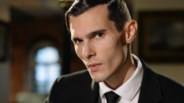 Mysterious man in suit exudes noir vibes in dimly lit room.