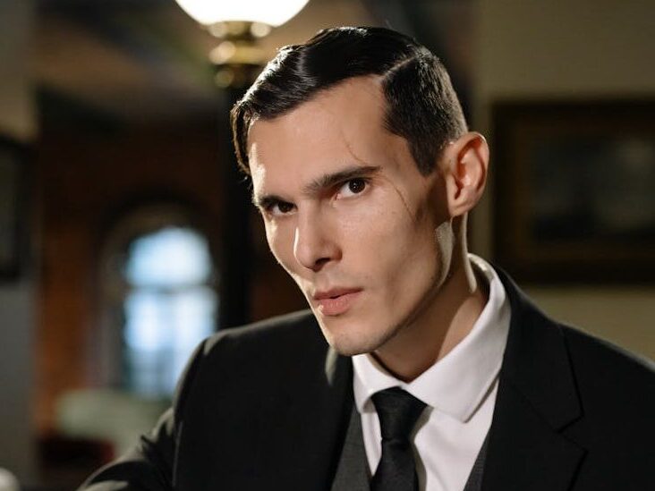 Mysterious man in suit exudes noir vibes in dimly lit room.