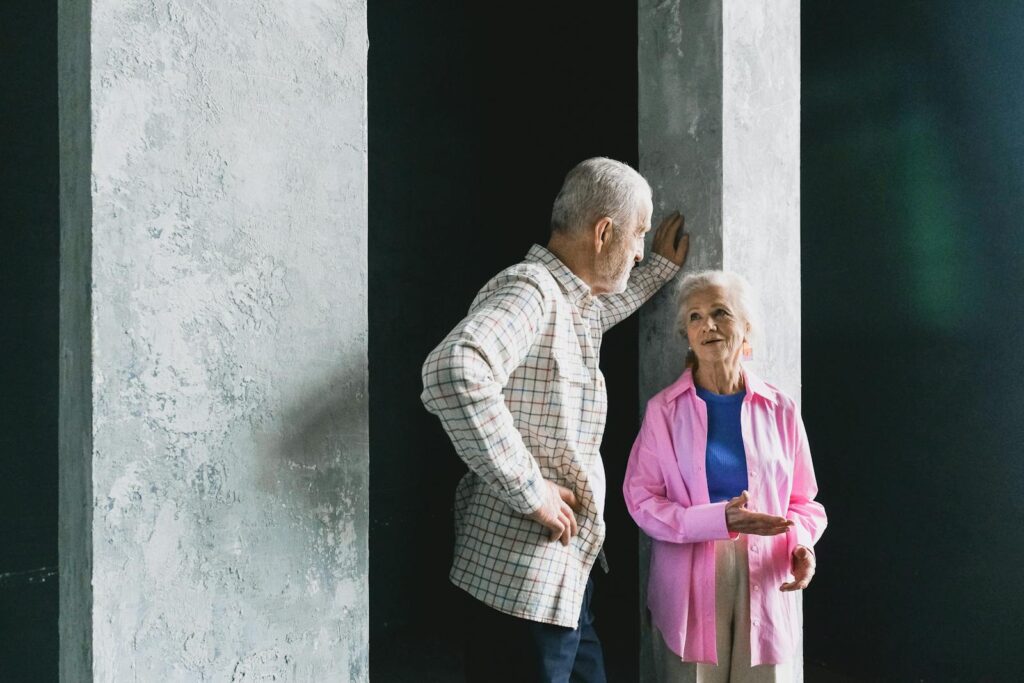 Elderly couple engaging in a warm conversation indoors, showcasing affection and happiness.