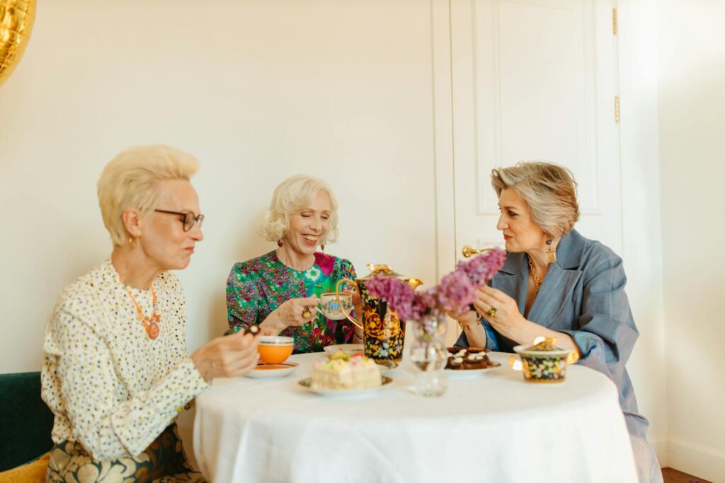 A warm gathering of senior women enjoying tea at a beautifully set table, sharing conversation and laughter.