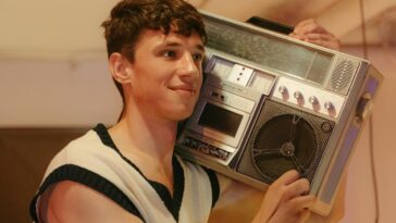 Smiling teenager holding a vintage boombox, embracing retro 80s vibes indoors.