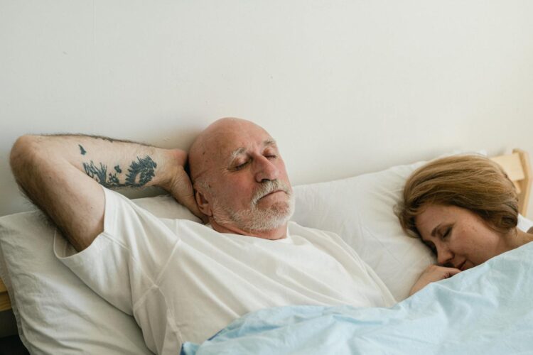 Peaceful elderly couple sleeping together in bed, showing relaxation and comfort.