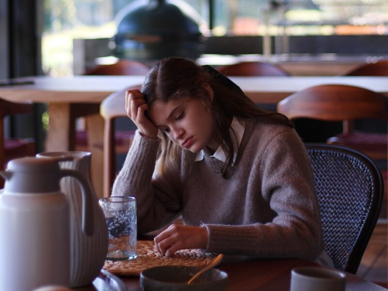 woman in gray long sleeve shirt sitting on brown wooden chair