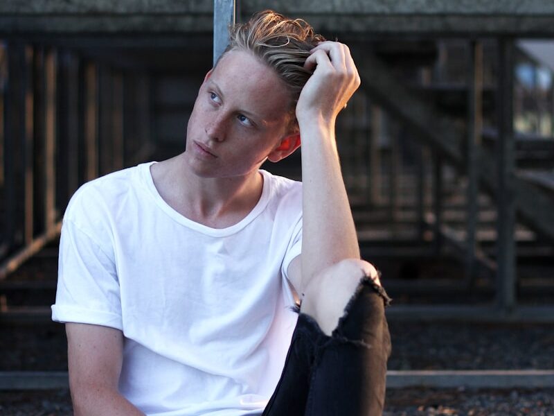 man sitting on floor wearing white crew-neck T-shirt