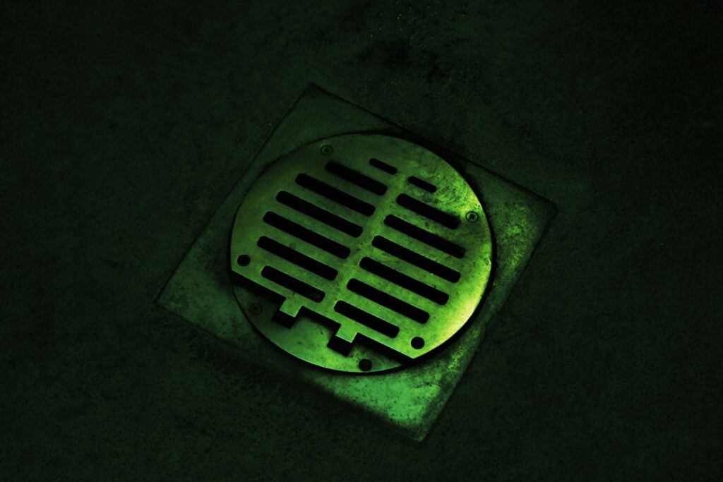 A drain in the ground with a green light on it