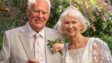Elderly couple in wedding attire holding hands outdoors