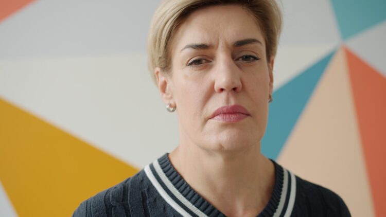 A woman with short blonde hair and a serious expression.