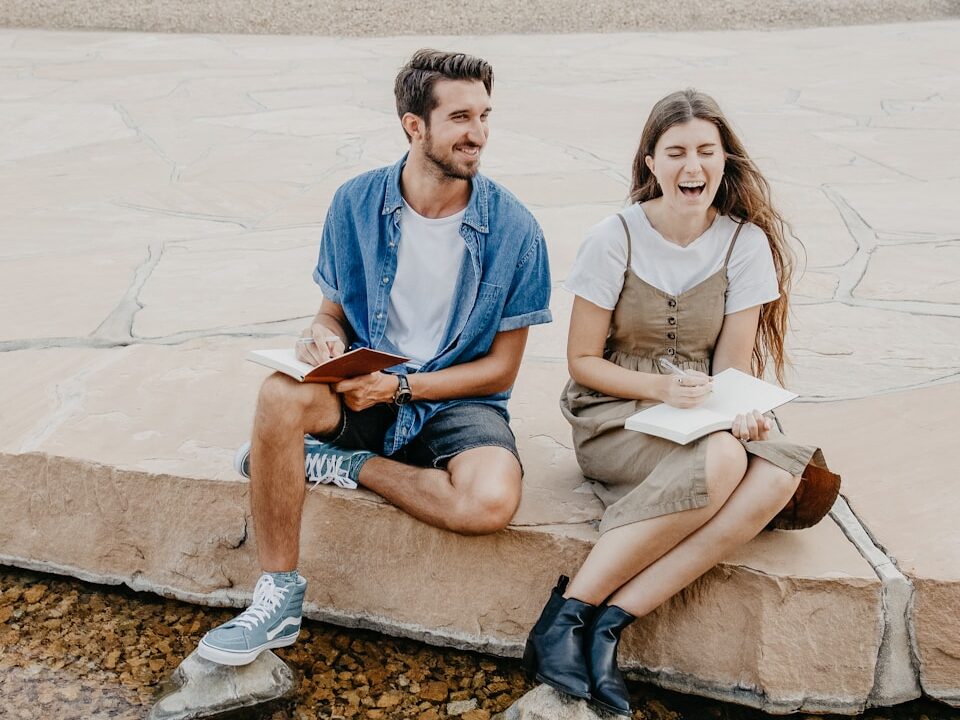 man and woman sitting side by side holding notebooks