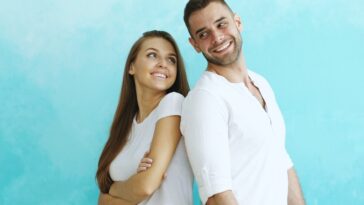 Couple smiling back to back against blue wall