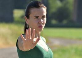 A woman in a green dress making a stop sign