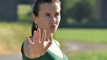 A woman in a green dress making a stop sign