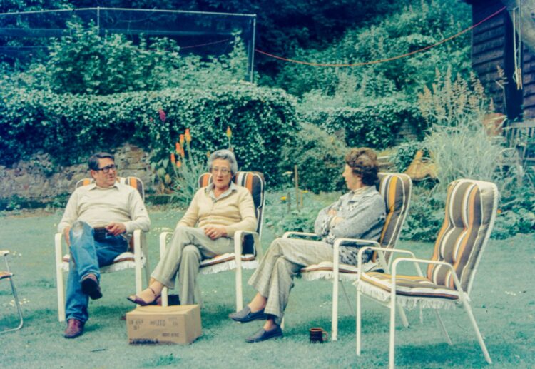 Three people relax in chairs outdoors.