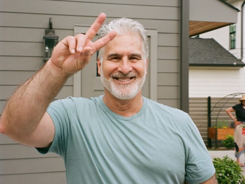 Man gives peace sign, smiling brightly.