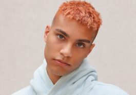 boy in white hoodie standing near white wall