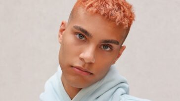 boy in white hoodie standing near white wall