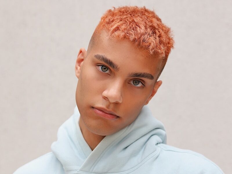 boy in white hoodie standing near white wall
