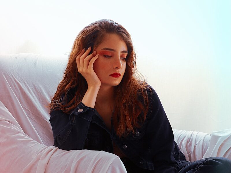 a woman sitting on a couch with her hand on her head