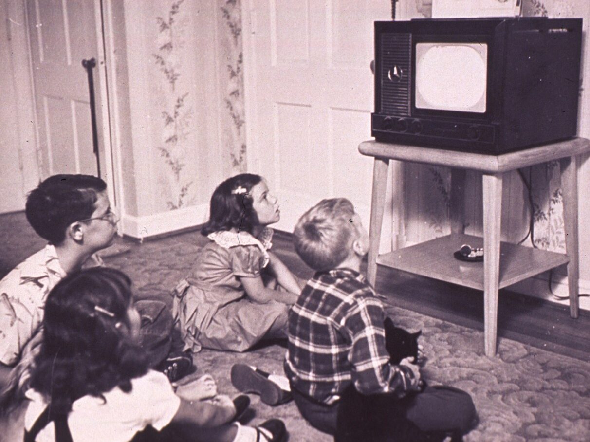 a group of children sitting on the floor in front of a tv